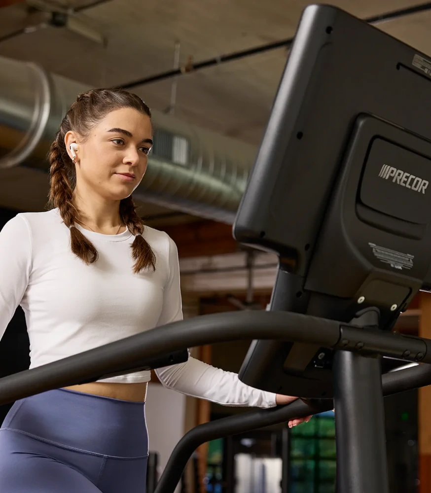 Woman using Precor cardio equipment in a custom gym